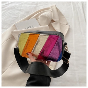 Detail of metallic rainbow stripes on a small crossbody bag with a wide nylon strap
