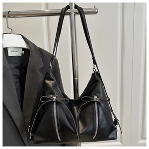 Close-up of black PU leather tote bag with silver zippers and decorative bow detail