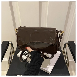 Détail d'un sac à bandoulière en cuir verni brillant avec boucle dorée et sangle