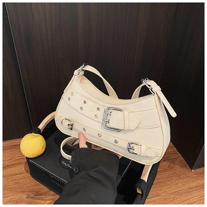 Detail view of cream crescent bag featuring silver buckles and punk motorcycle style rivets