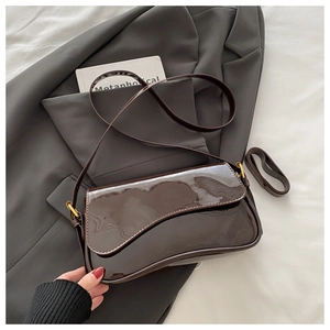 Détail du sac sous le bras en cuir verni marron foncé avec rabat ondulé et boucle dorée
