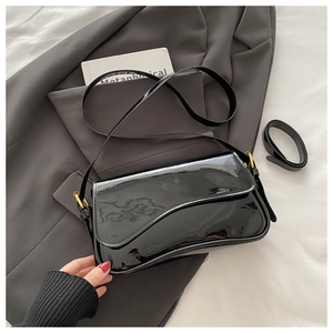 Détail du sac à bandoulière en cuir verni noir montrant la texture brillante et le fermoir