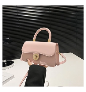 Detail of pink faux leather handbag with golden ring clasp and detachable shoulder strap