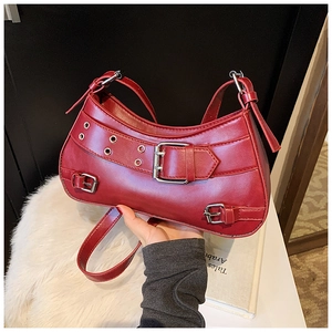 Detail shot of a burgundy punk style crescent bag with silver buckles and grommets