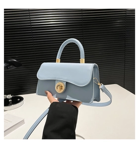 Detail of light blue crossbody bag with gold round twist lock and slender handle
