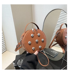 Close-up of a brown circular crossbody bag with silver studs and mirror reflection view