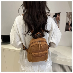 Brown corduroy mini backpack with adjustable straps shown in back view on model