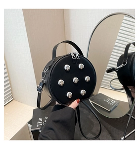 Detail view of round black crossbody bag with silver sphere studs and top handle