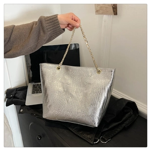Close-up of silver crocodile embossed tote bag with elegant gold metal chain strap