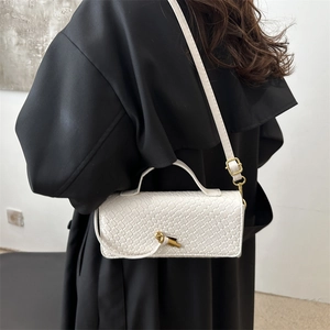 Elegant white textured baguette bag with gold twist lock shown on a model