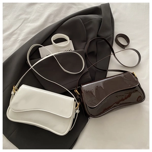 Détail des sacs à bandoulière en cuir verni blanc et café sur un blazer gris