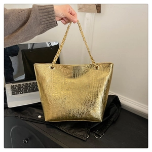 Close-up of golden crocodile pattern tote bag with metallic chain strap and texture