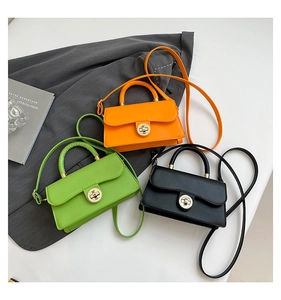 Three leather crossbody bags in orange green and black colors with gold turn-lock hardware