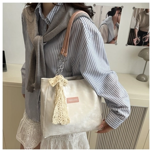 Detail of white velvet tote bag with pink straps and elegant lace bow charm