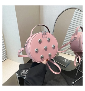 Pink round leather crossbody bag with silver rivets and dual zipper detail