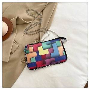 Détail du sac à main géométrique coloré avec rivets argentés et bandoulière chaîne