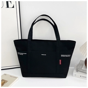 Detail of black canvas tote bag showing double front pockets and minimalist letter print