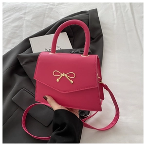 Detailed view of the rose pink handbag featuring a gold metal bow lock and matte PU texture