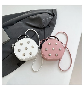 Detail view of round crossbody bags in white and pink with stylish metal rivet studs