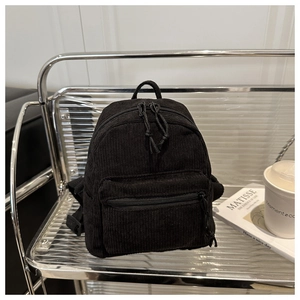 Detail shot of black corduroy mini backpack showing dual zippers and front pocket texture