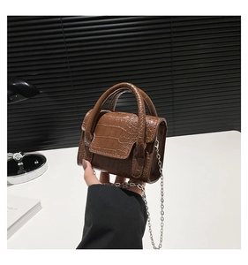 Detail of dark brown crocodile embossed mini square bag with metal chain and top handles
