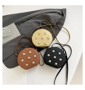 Detailed close-up of mini round crossbody bags with rivets in gold, brown, and black colors