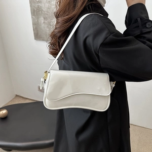 Sac sous le bras chic en cuir verni blanc avec détails dorés porté par un mannequin