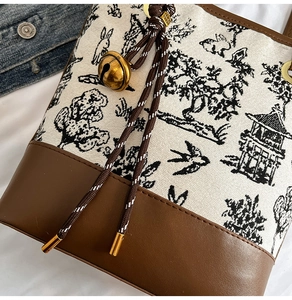 Detail of canvas bucket bag featuring toile de jouy rabbit print and golden ball charm