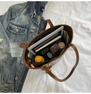 Top view of brown leather bucket bag showing large interior capacity with a tablet and books