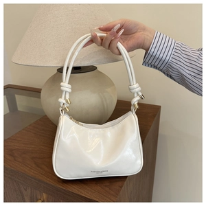 Close-up of white glossy faux leather hobo bag with knotted handle and gold hardware