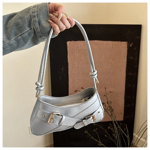 Detail of silver metallic underarm bag showing buckle straps and knotted shoulder strap