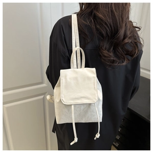 Détail d'un mini sac à dos blanc crème avec texture plissée et cordon de serrage