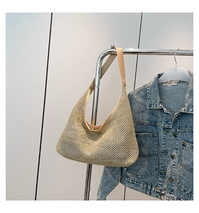 Close-up of beige woven tote bag hanging on a rack with a denim jacket background