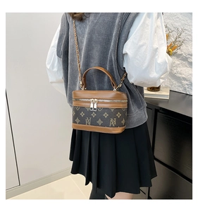 Rear view of model carrying a vintage brown monogram crossbody bag with chain strap