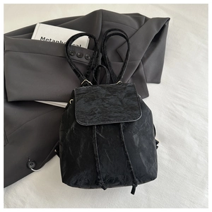 Détail d'un sac à dos noir en tissu texturé avec cordon de serrage et rabat
