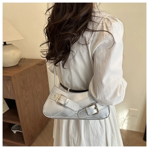 Detail of silver metallic shoulder bag with double belt buckles and gold-tone hardware