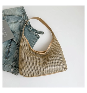 Detail of champagne gold woven texture and camel leather shoulder strap on tote bag
