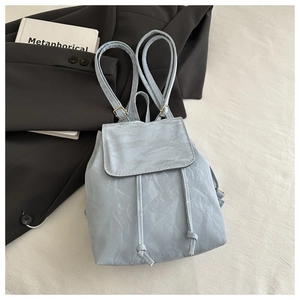 Détail du sac à dos bleu clair à texture froissée avec cordon et fermeture à rabat