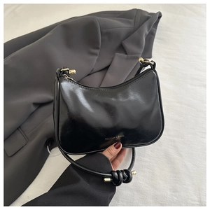 Close-up of black glossy hobo bag with gold hardware and stylish knotted strap detail