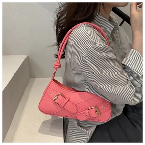 Detailed view of pink leather baguette bag with buckle straps and knotted shoulder strap