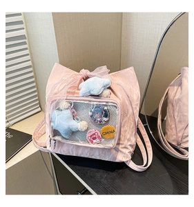 Detail view of pink nylon ita bag with transparent window, badges and a bow accent