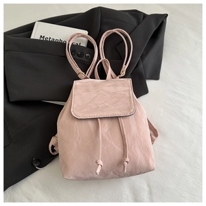 Détail d'un mini sac à dos rose brillant avec texture froissée et fermeture à cordon
