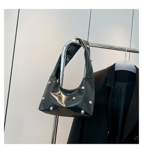 Detail of trendy black crossbody bag with silver stud accents and glossy leather texture