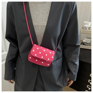 Gros plan d'un mini sac à pois rose vif avec une fine bandoulière réglable