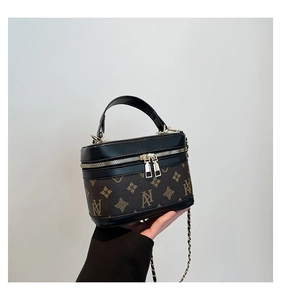 Close-up of cylinder box bag with monogram pattern and gold double zipper detail