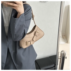 Detail of apricot saddle shoulder bag with decorative belts and metal buckles in mirror selfie