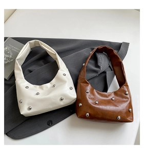 Detailed view of silver metallic studs on cream and brown vintage PU leather handbags