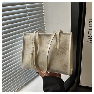 Detail of cream tote bag with gold butterfly print and elegant tassel accessory