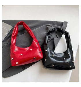 Detail of red and black studded hobo bags on grey fabric background with books