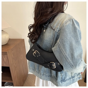 Detail of black leather shoulder bag with metal buckle and eyelets in biker style
